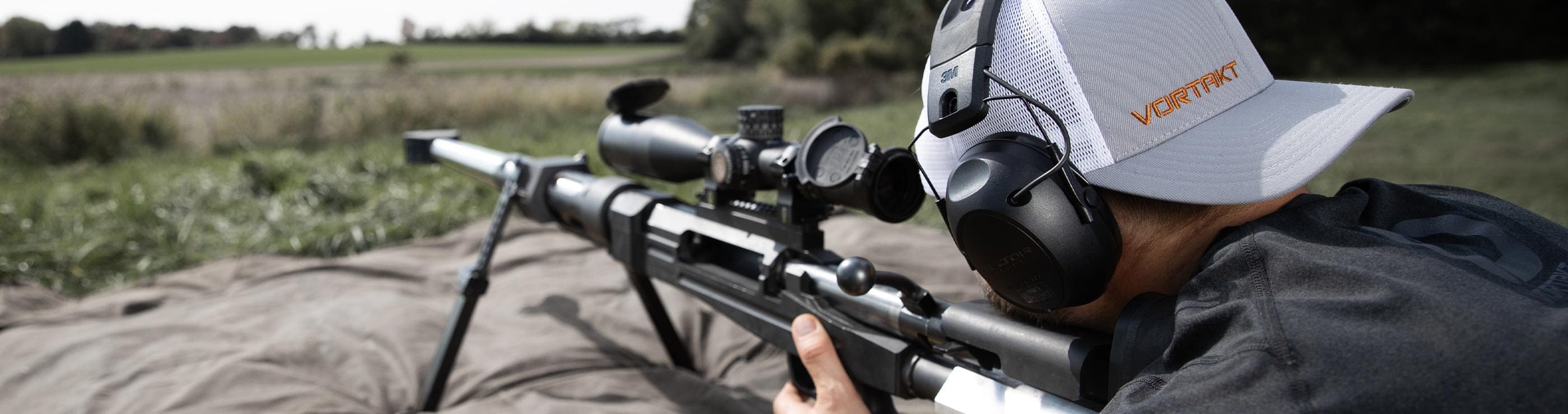 Chad laying on the ground shooting a 50 caliber barrerl with a Vortakt hat on